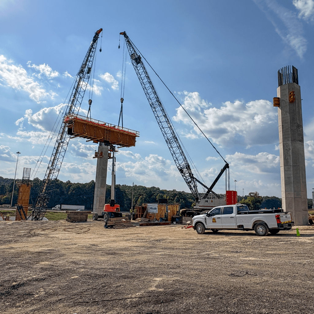Distance shot of the finished concrete columns, with two cranes lowering the SUPER PLATE GIRDER pier cap into place to start the next pour.